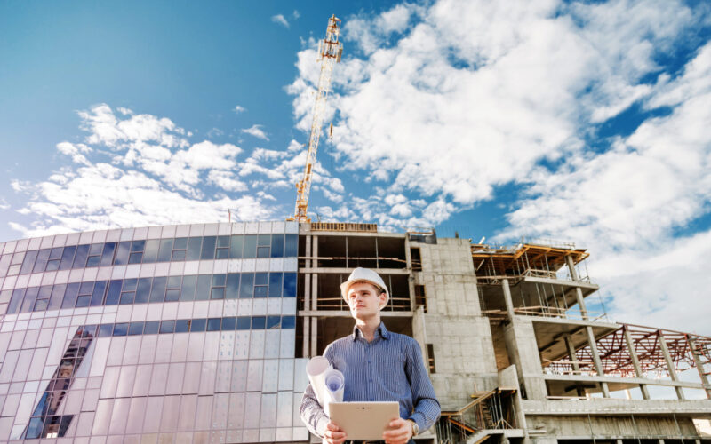 Construction manager controlling building site with plan